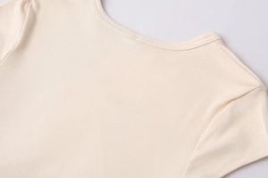 Detail of round neckline and premium ribbed knit texture on a cream summer dress