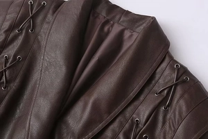 Detail view of the brown PU leather coat with metal eyelets and decorative lacing on shoulder