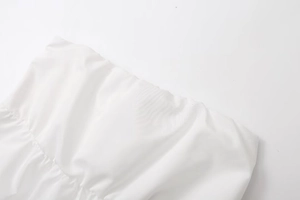 Close-up of elastic shirred edge on white strapless top with premium textured fabric