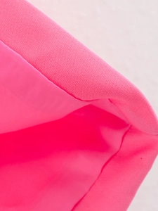 Macro shot of pink woven fabric texture and high-quality stitching on a fashion vest