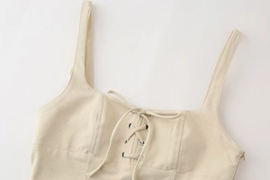 Detail of lace-up beige crop top with silver eyelets and cotton twill texture