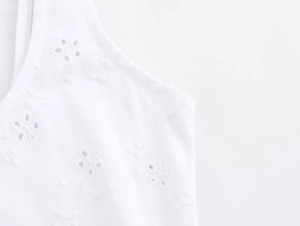 Gros plan sur la broderie florale et les détails ajourés d'une robe d'été blanche en coton
