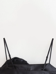 Detail of black satin camisole featuring adjustable straps and glossy silk-like texture