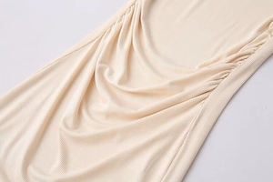 Close-up of cream ribbed knit fabric showing detailed side drawstring ruching design