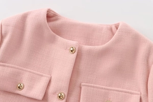 Nahaufnahme der rosa Tweed-Jacke mit Rundhals und dekorativen Goldknöpfen