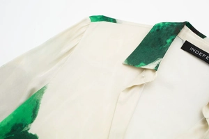 Détail du chemisier blanc avec imprimé marbré vert sur le col et étiquette de marque INDEFE
