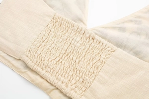 Detailed macro view of smocked fabric texture on summer beige embroidery crop top set