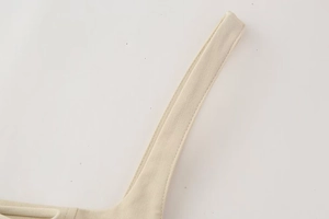 Detailed macro view of the double stitching on beige cotton twill midi dress shoulder straps