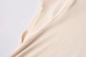 Close-up of ribbed fabric texture and neckline stitching on cream knit dress