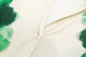 Détail de l'imprimé floral artistique vert et petit bouton sur chemise crème clair