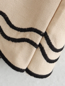 Macro di tessuto beige intrecciato con ricami ondulati neri e dettagli di consistenza