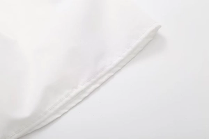 Close-up detail of high-quality double-stitched hem on a white summer crop top