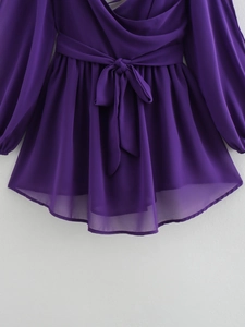 Detail of dark purple chiffon dress featuring waist tie-up bow and tiered translucent hem