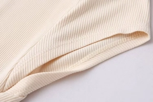Detail of light beige ribbed knit fabric showing fine stitching and soft texture