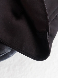 Close-up of industrial sewing on brown satin fabric showing smooth texture and stitching