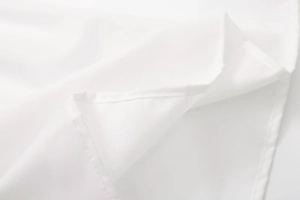 Detailed macro view of neat stitching on white cotton fabric hem for women's summer top