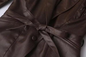 Detail of dark brown leather coat featuring waist belt tie and fine stitching quality