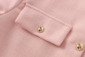 Details einer rosa Tweed-Jacke mit goldenen Knöpfen und flacher Taschenklappe