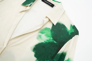 Détail de l'encolure souple et de l'imprimé artistique vert sur une chemise chic