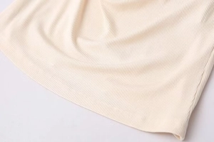 Close-up of beige ribbed knit fabric showing detailed texture and hem stitching