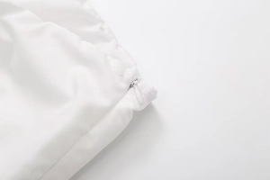 Detailed macro view of high-quality invisible zipper closure on white slim-fit crop top