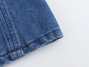 Detailed close-up of dark blue denim fabric with reinforced double stitching and twill texture