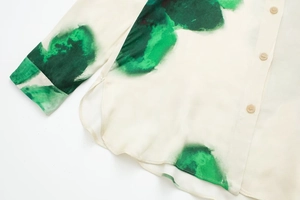 Détails de la chemise crème soyeuse avec imprimé à l'encre verte et boutons beige