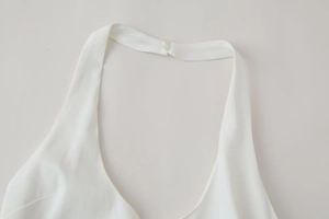 Detail view of the halter neckline and button closure on white layered summer dress
