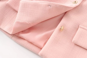Detailaufnahme der rosa Tweed-Textur mit goldenen Knöpfen und edlem Seidenfutter der Jacke
