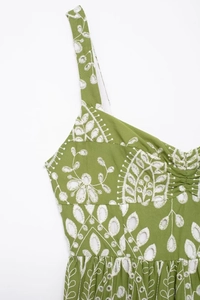 Close-up of grass green dress featuring delicate white floral embroidery and eyelet details