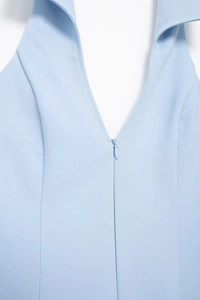 Close-up of light blue halter neck top featuring a deep V-neckline and zipper detail