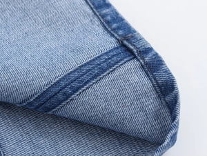 Close-up of durable light blue denim fabric with precise stitching details on the hemline