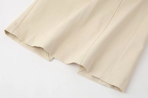 Detail of light beige midi dress showing vertical stitching and twill fabric texture