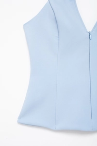 Detail showing the deep V-neck and invisible zipper on a light blue summer top