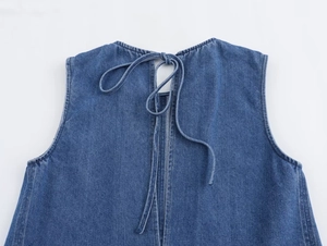 Detail of light blue denim dress back featuring cut-out design and adjustable tie-up ribbons