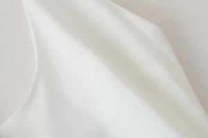 Close-up of white linen fabric texture and high-quality stitching on summer dress detail