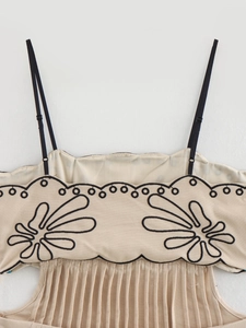 Dettaglio dell'abito beige con ricamo floreale nero e sottili spalline regolabili