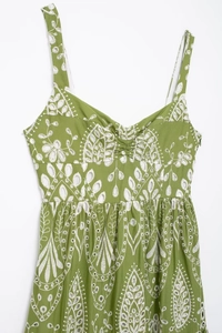 Detail of green summer midi dress featuring intricate white hollow embroidery and V-neck