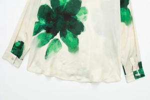 Détail de l'imprimé floral à l'encre verte sur le poignet en satin avec bouton élégant