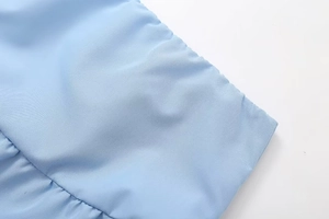 Detailed close-up of light blue textured fabric with delicate ruffled edge detailing