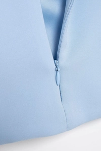 Close-up of seamless invisible zipper detail on light blue woven fabric top