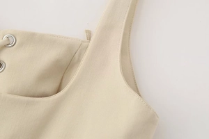 Detailed view of beige midi dress featuring twill fabric and silver metal eyelets