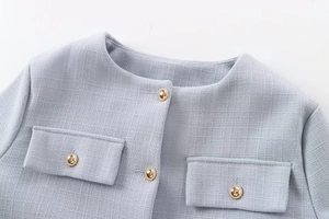 Detailansicht der hellblauen Tweed-Jacke mit Goldknöpfen und gewebter Textur