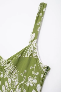 Detail of green summer dress featuring white eyelet floral embroidery and hidden zipper