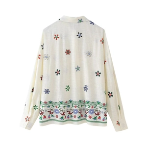 Détail du dos d'une chemise en lin blanc cassé avec des broderies florales complexes