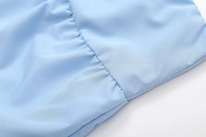 Macro shot of light blue fabric showing detailed ruched stitching and fine texture