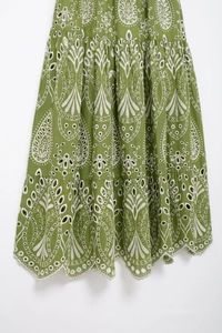 Close-up of white paisley eyelet embroidery on a green tiered bohemian midi skirt