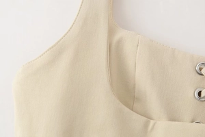 Detailed macro view of beige twill fabric featuring a silver metal eyelet and fine stitching