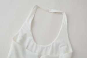Detail view of white halter neck dress featuring metal hook closure and hidden zipper detail