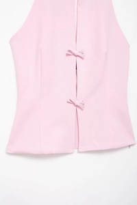 Detaillierte Nahaufnahme des rosa Neckholder-Tops mit zwei dekorativen Schleifen auf Stoff